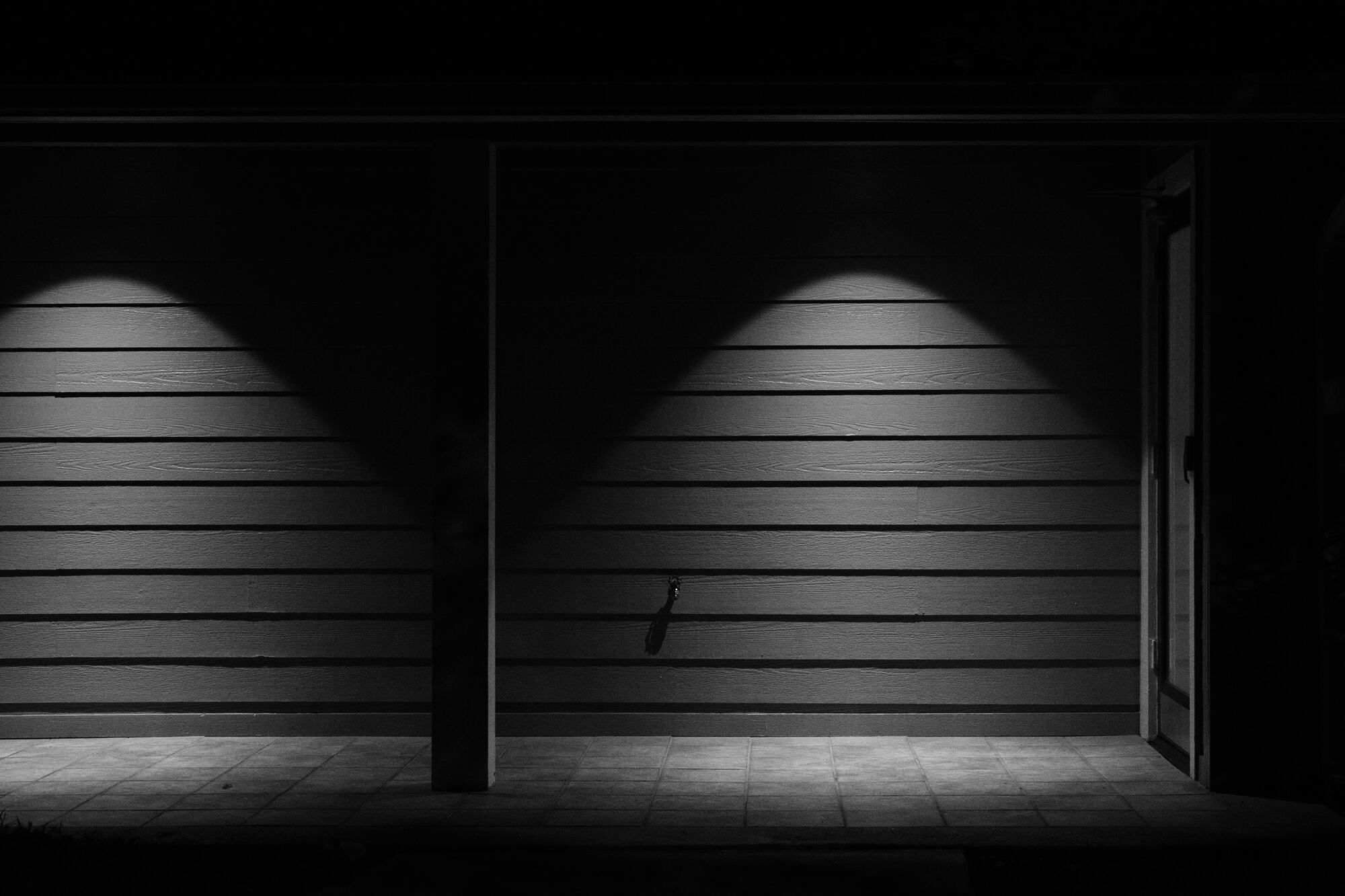 A darkened wall and doorway lit by two pools of light